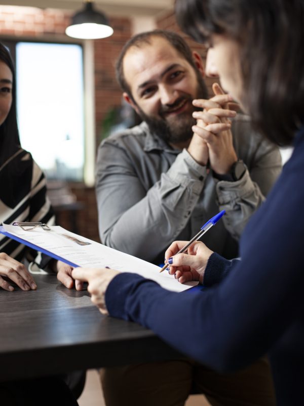 Closeup of caucasian woman holding a clipboard and signing her job offer opportunity at startup office. Young female individual with a pen in hand, completing her application form.